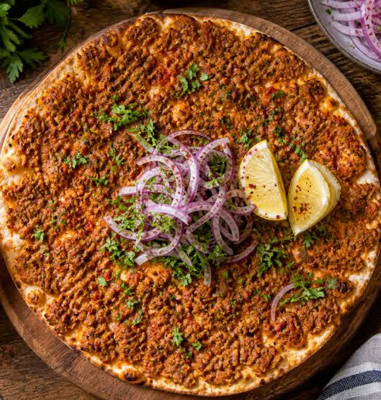 Lahmacun topped with seasoned minced meat, red onion, herbs and lemon